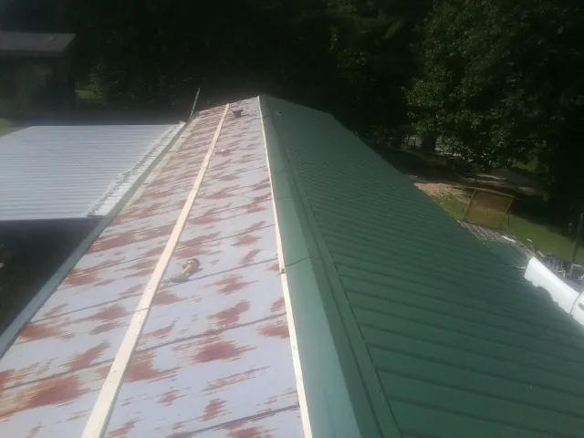 Old rusted panels beside newly installed green metal roofing — Wind Damage Roof Repair by Roofing Brothers in Dania