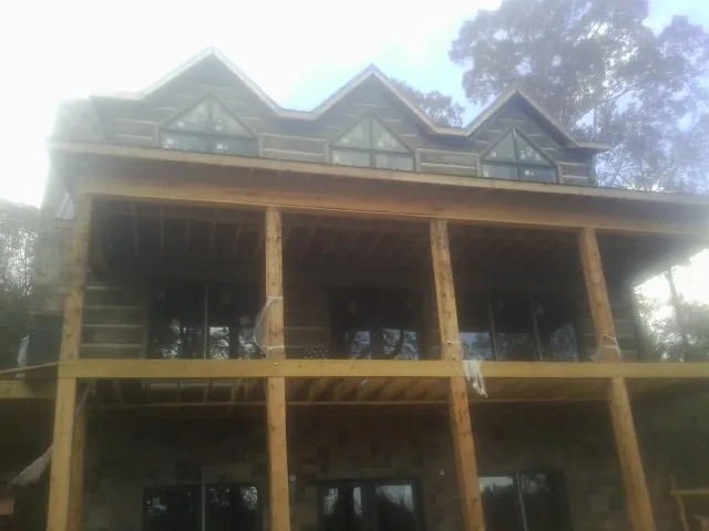 Dormers and porch framing on a large log home under construction — Roof Coating work by our crew in Dania