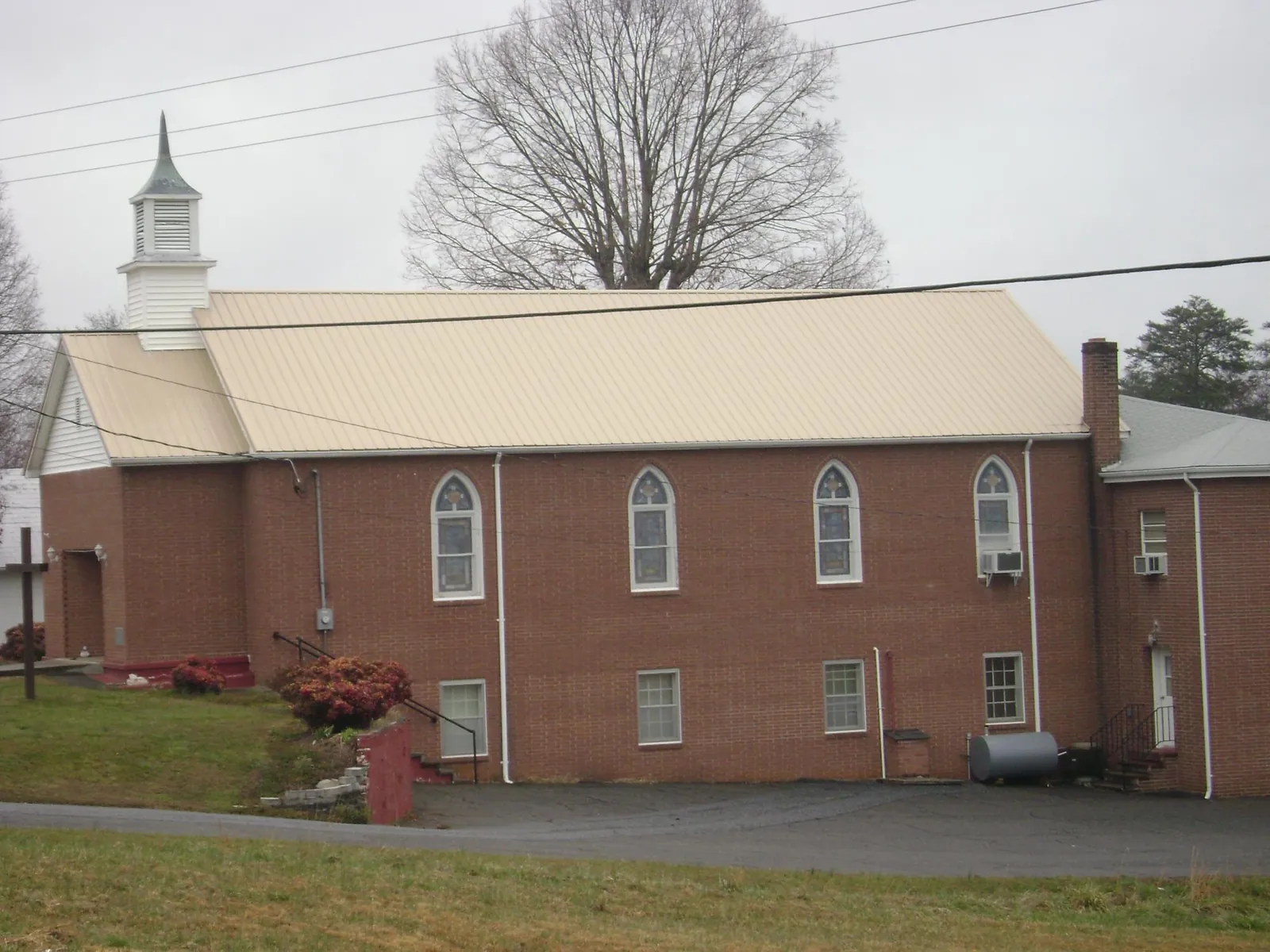 New tan metal roof on a brick church with a white steeple in Dania