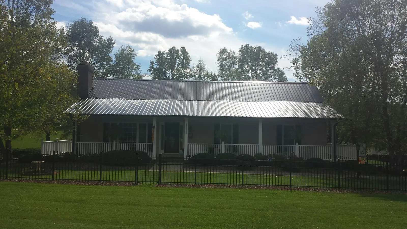 Gray metal roof on a brick ranch with a full width front porch — Gutter Guard Installation work by our crew in Dania